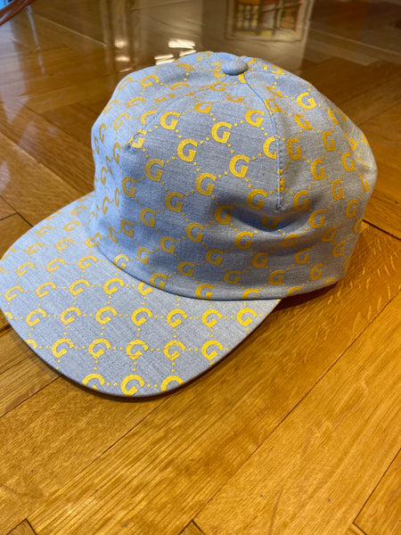 a side view of a silver gray hat with gold "gucci" style Gigantic G's in a pattern all over